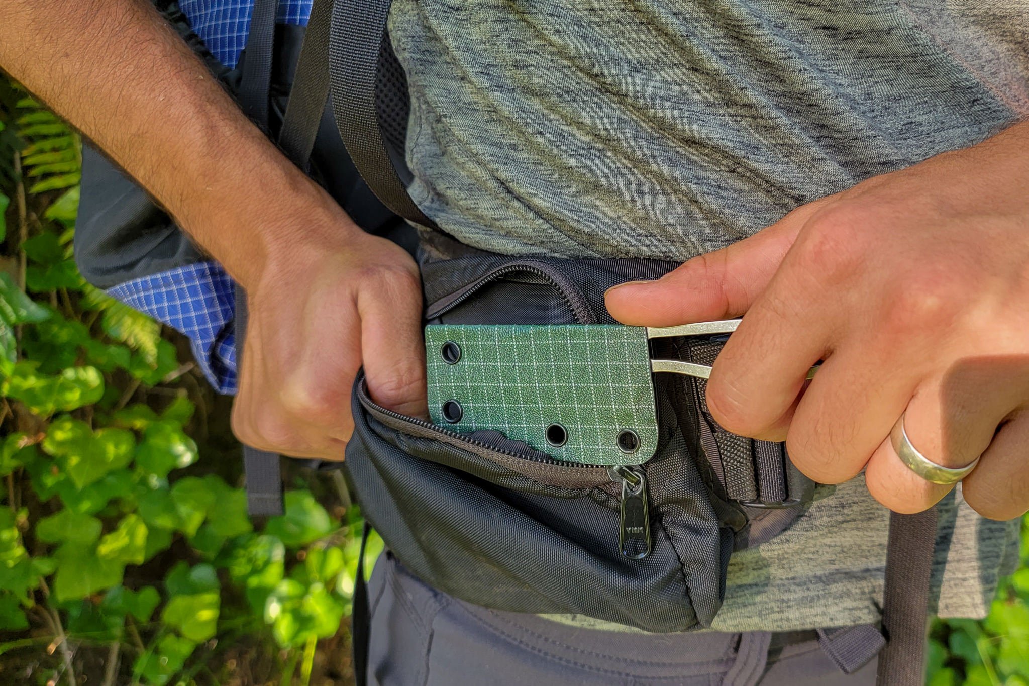 Closeup of a backpacker putting the ULA Alpha Knife in the hip belt pocket of his ULA Circuit Backpack