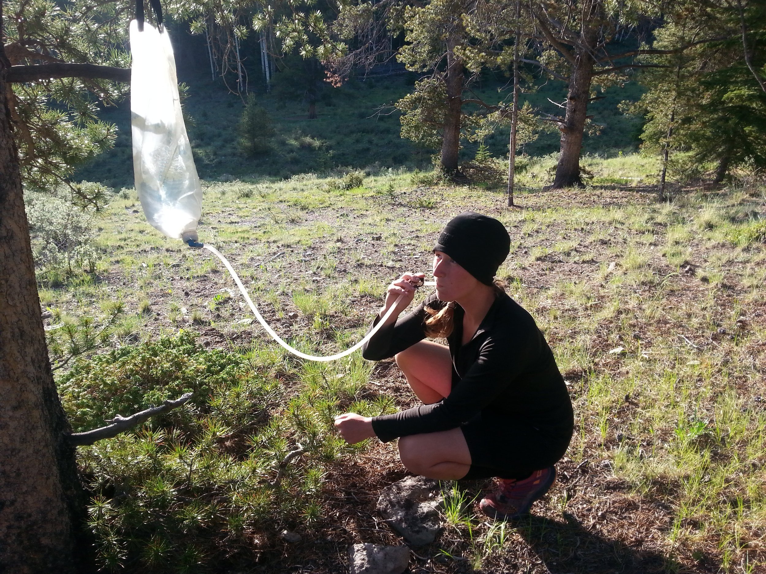 A backpacker drinking directly from the clean reservoir of the Platypus GravityWorks Water Filter