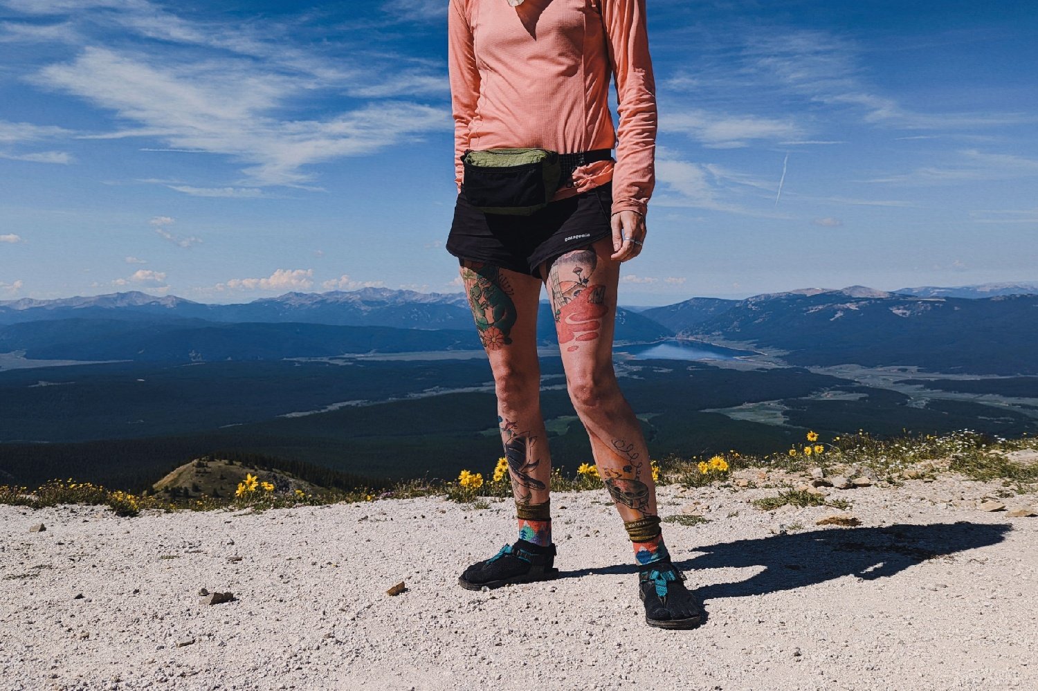 A torso down view of a hiker wearing a LiteAF Featherweight Fanny Pack in front of a mountain view