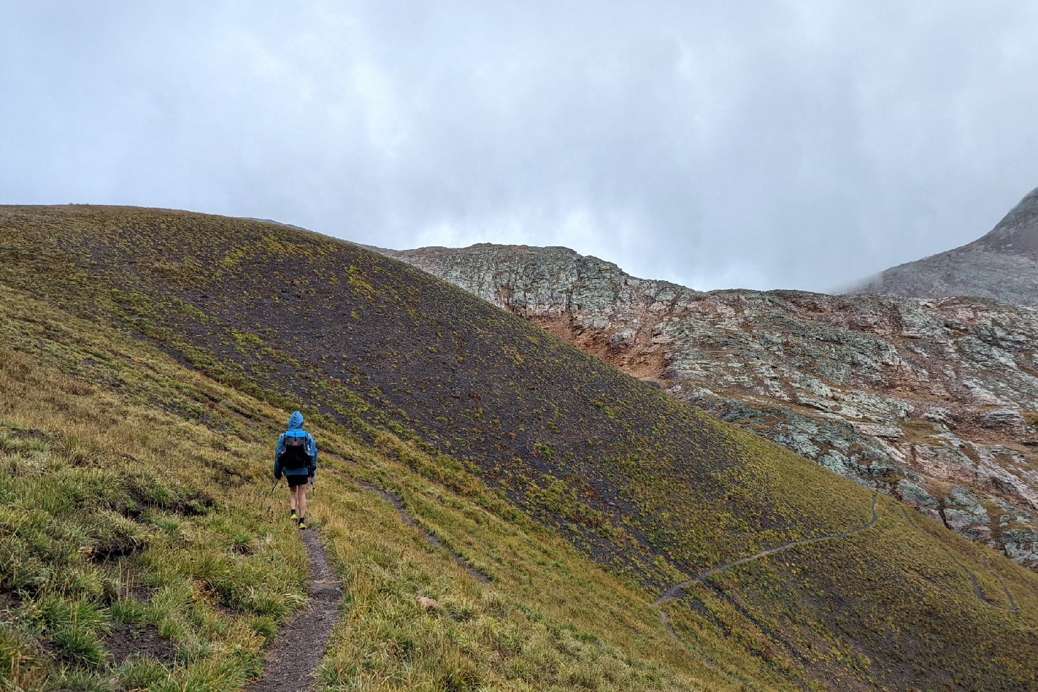 A hiker walking on the Colorado Trail with a grey sky above
