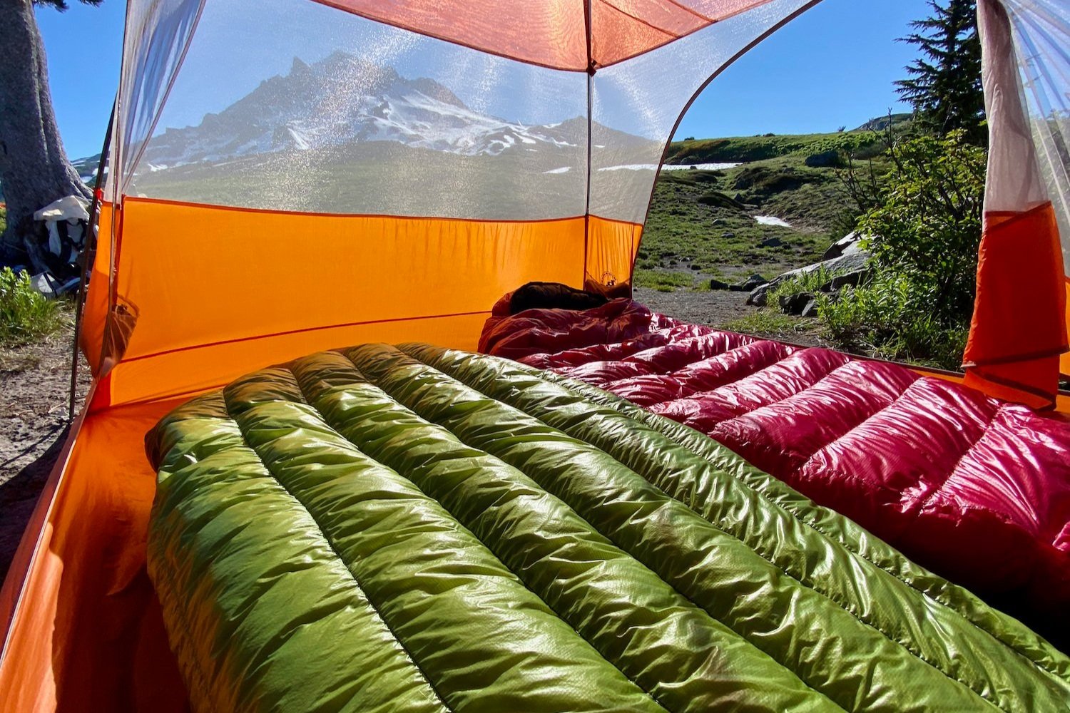 The Zpacks Classic Sleeping Bag laying next to the Western Mountaineering Alpinlight in a tent with a mountain view