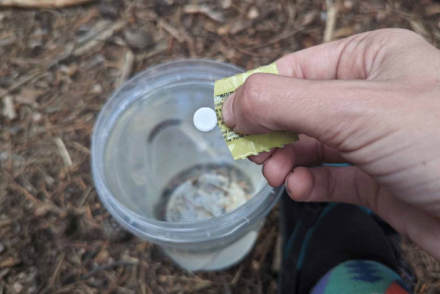 A person dropping a Katadyn Micropur Tablet into some water