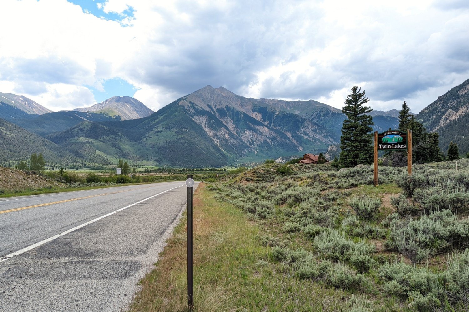 A sign on the side of a road welcomes you into Twin Lakes Colorado with a big mountain view