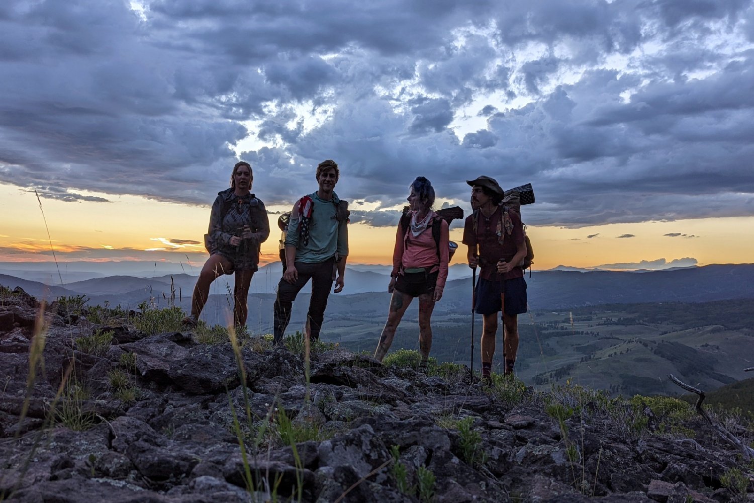 A group of four hikers standing in front of a sunset view on the Colorado Trail