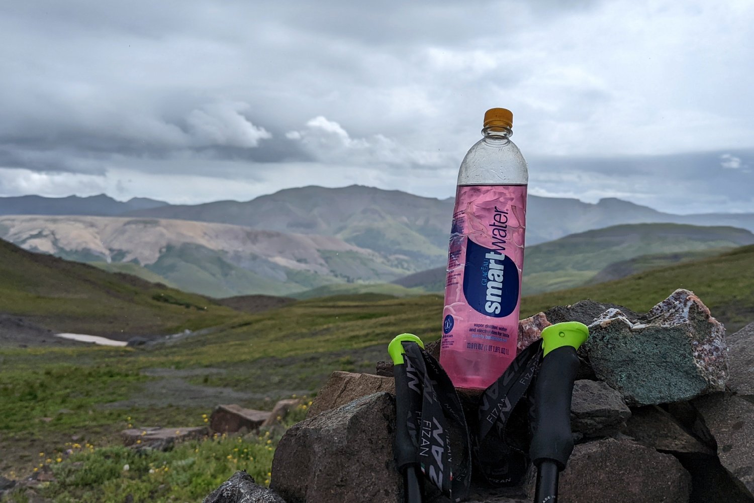 A smartwater bottle with an Ultima Hydration mix in it with mountains in the background