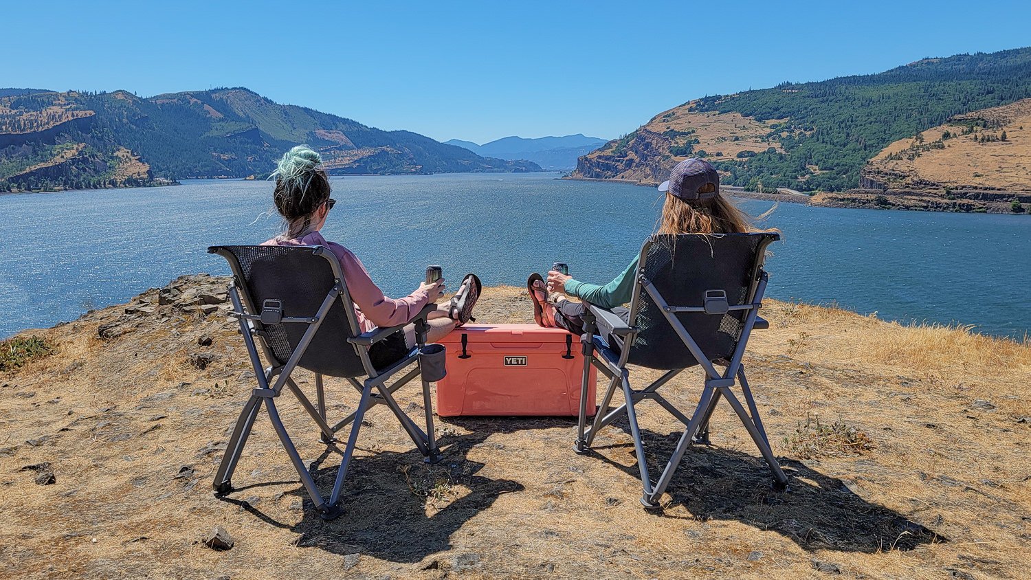 Two women sitting in the YETI Trailhead Chairs with their feet up on the YETI Tundra Cooler