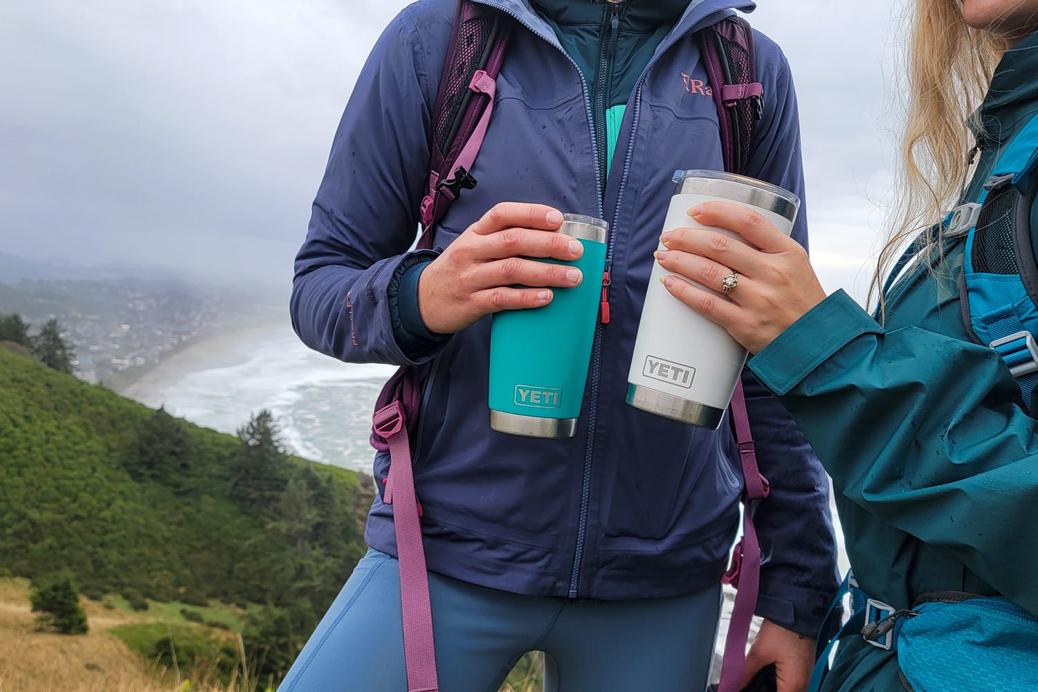 Closeup of two women using YETI Rambler Tumblers on a cold, fall day hike at the coast