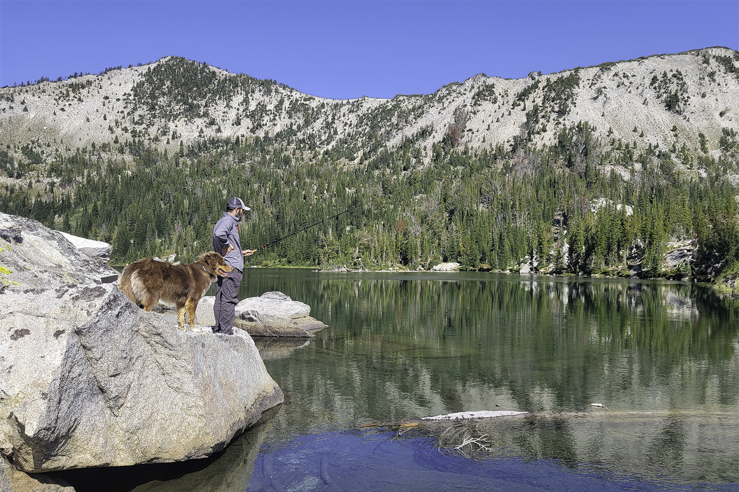 A backpacker wearing the Columbia Silver Ridge Lite sun shirt fishing in an alpine lake