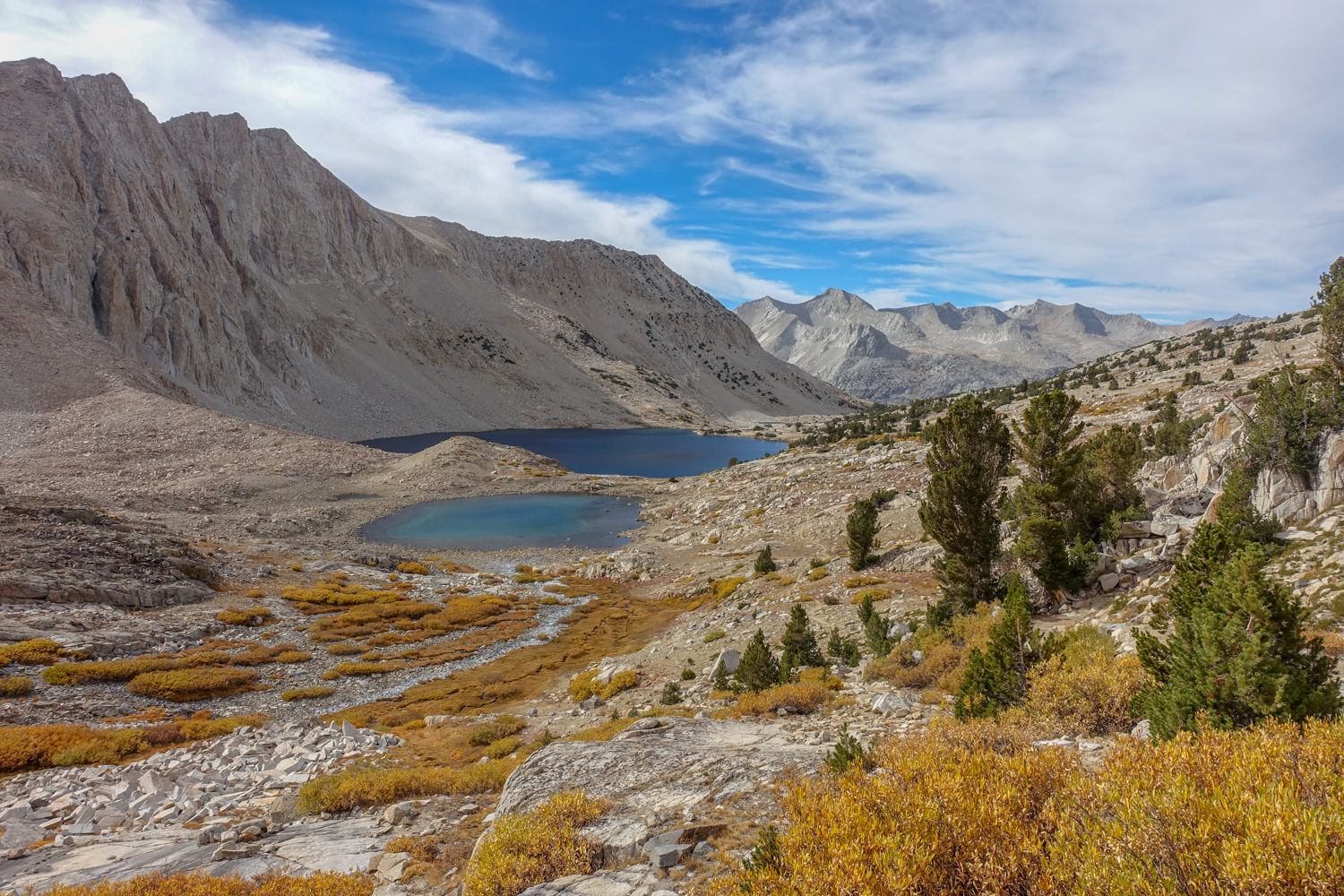 Two alpine lakes below a mountain with golden brush in the foreground