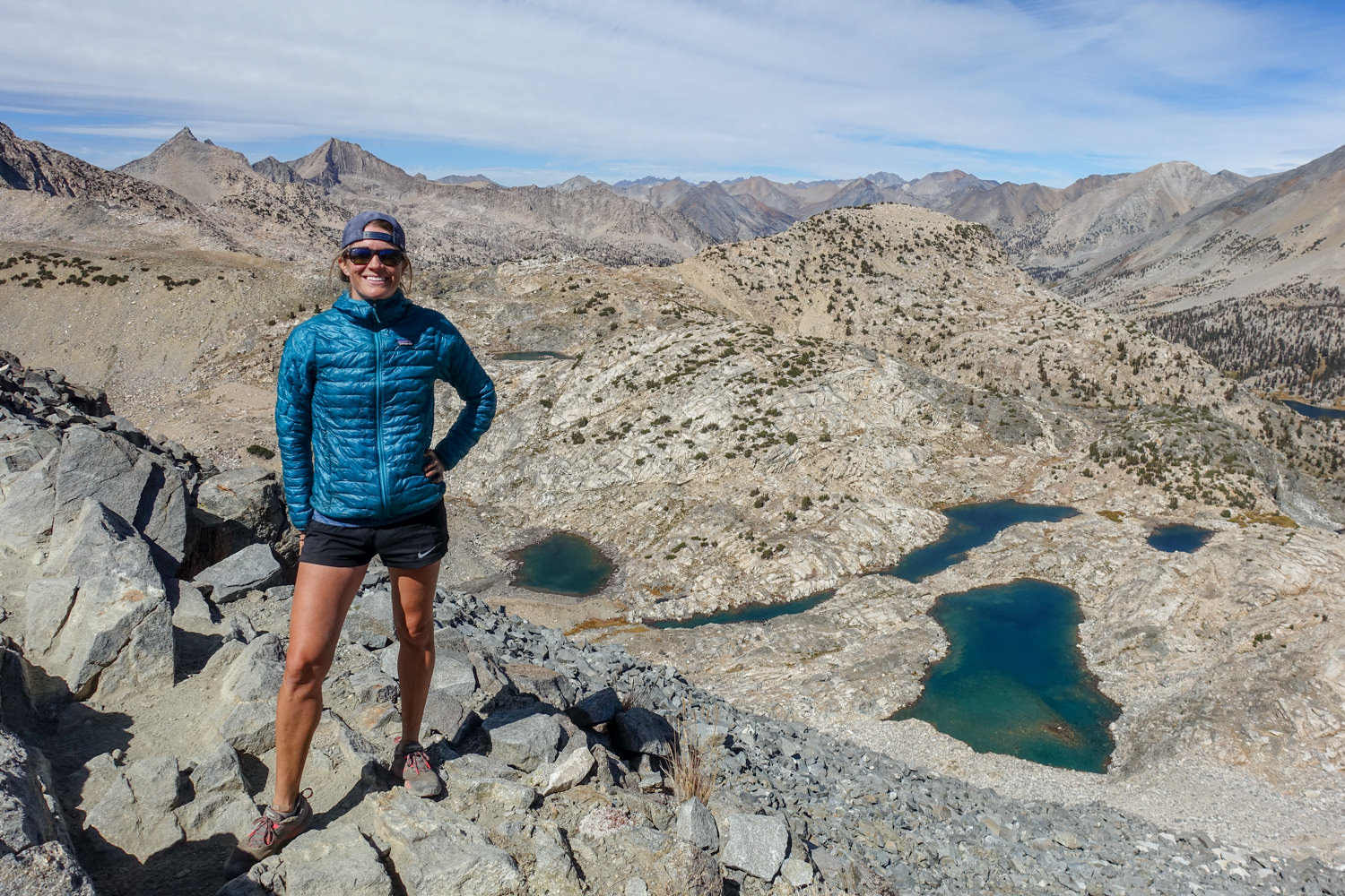 JMT backpacker posing above several high alpine lakes surrounded by mountains.