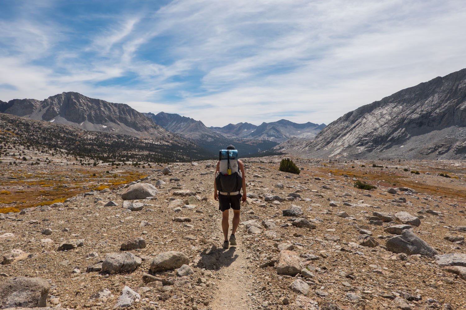 Backpacker hiking the John Muir Trail through a basin