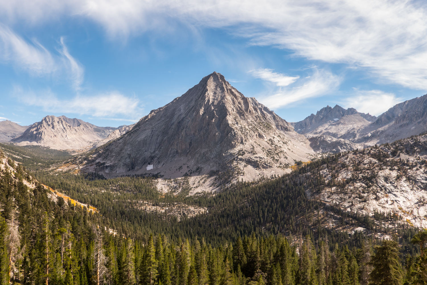 a mountain, conical and symmetrical in shape framed by trees slopes.