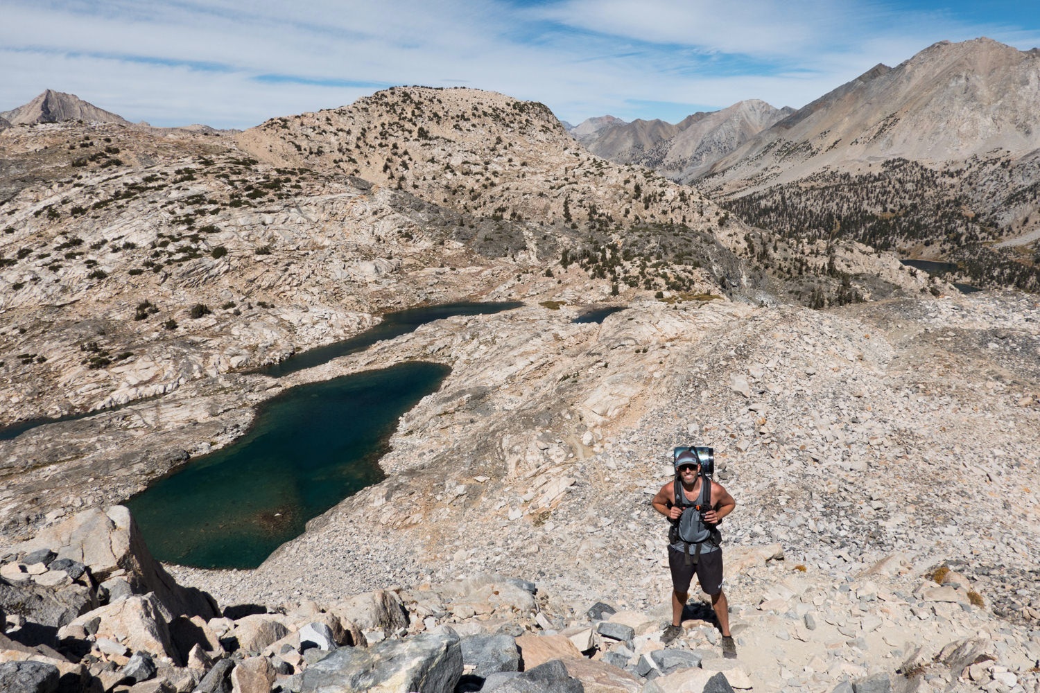 Backpacker posing above alpine lakes on the John Muir Trail