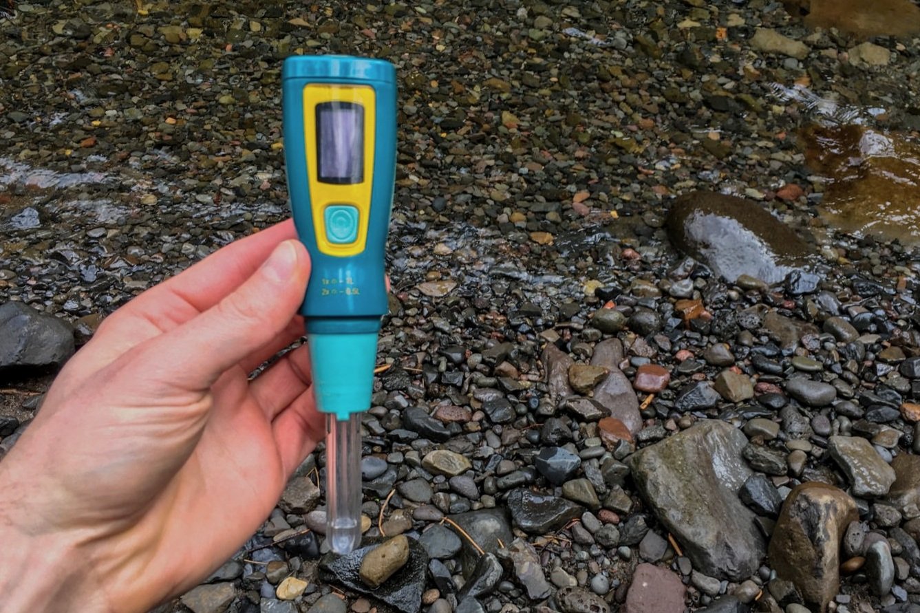 A steripen ultra water purifier held in front of a stream