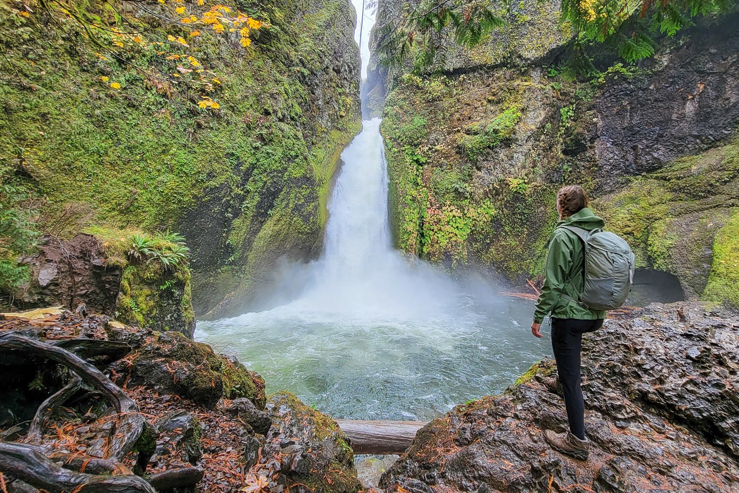A day hiker wearing a rain jacket on a waterfall hike