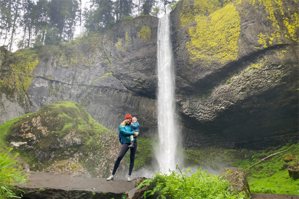 A mom holding her son near a waterfall