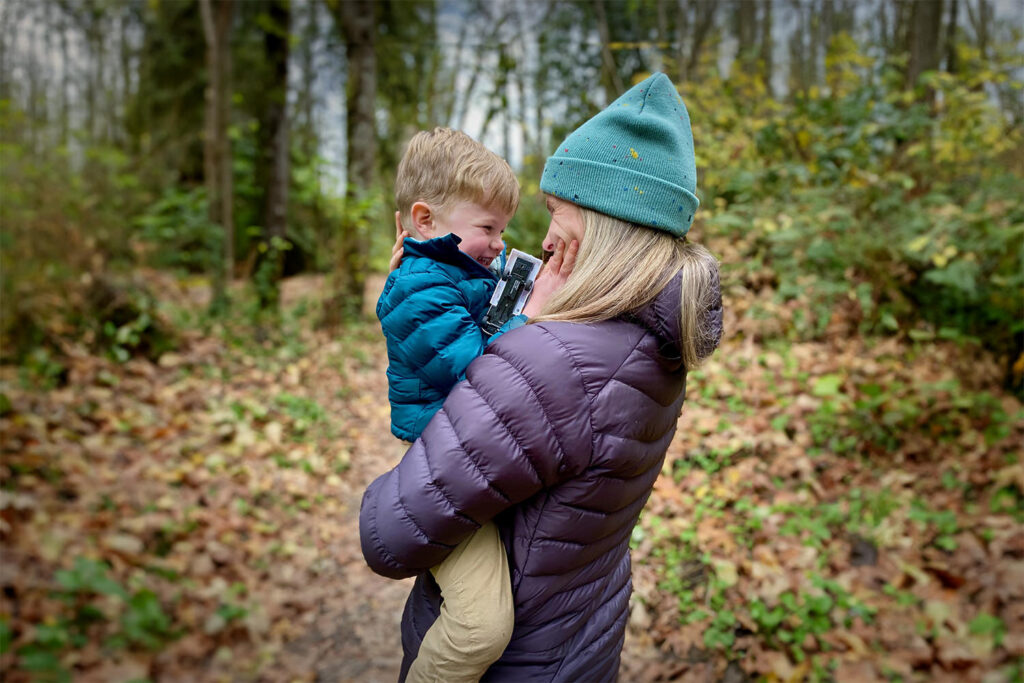 A mom holding her son close while hiking in the forest
