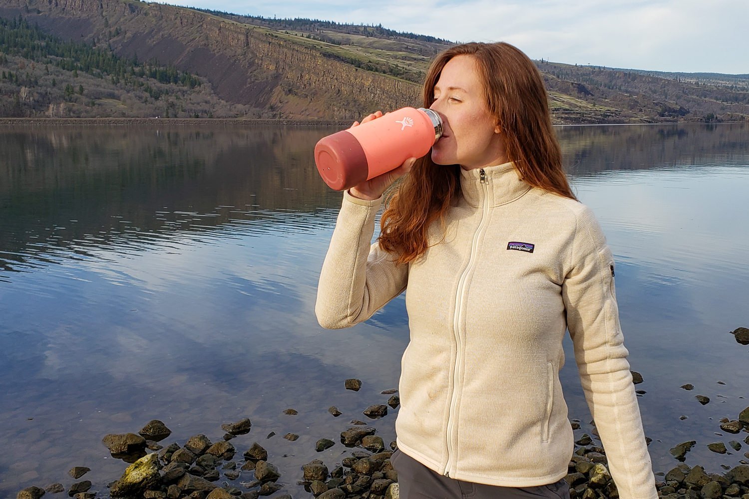 A hiker drinking from a pink Hydro Flash with the Columbia River Gorge in the background