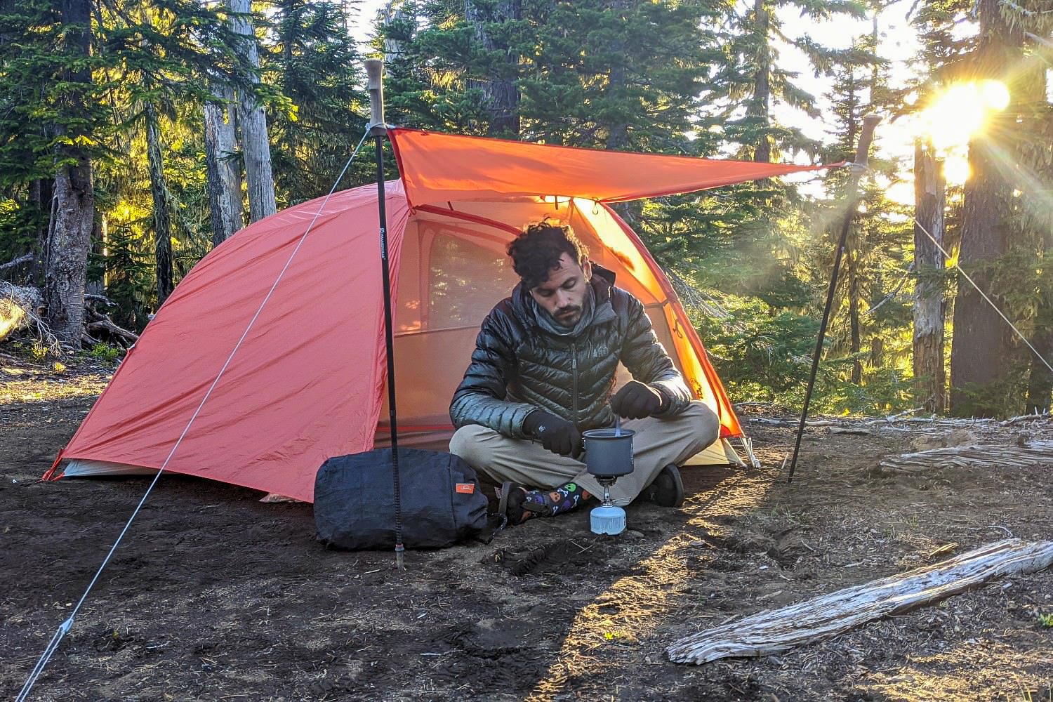 A backpacker cooking under the awning of the Big Agnes Copper Spur