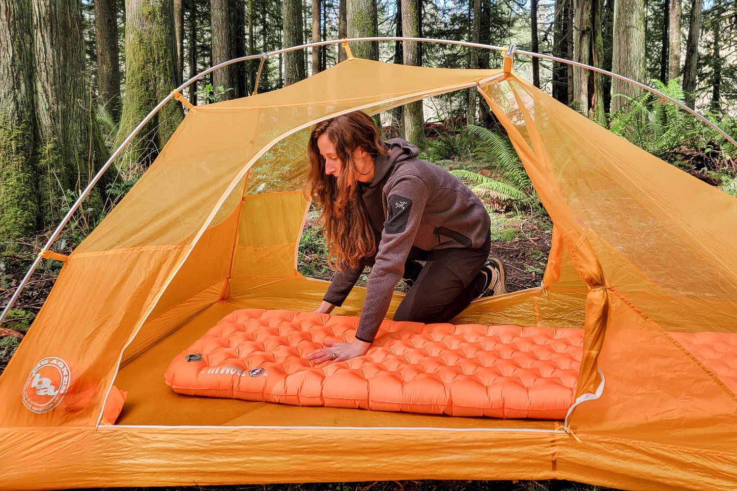 A hiker kneeling in a Big Agnes tent with their hand on a Big Agnes Zoom UL