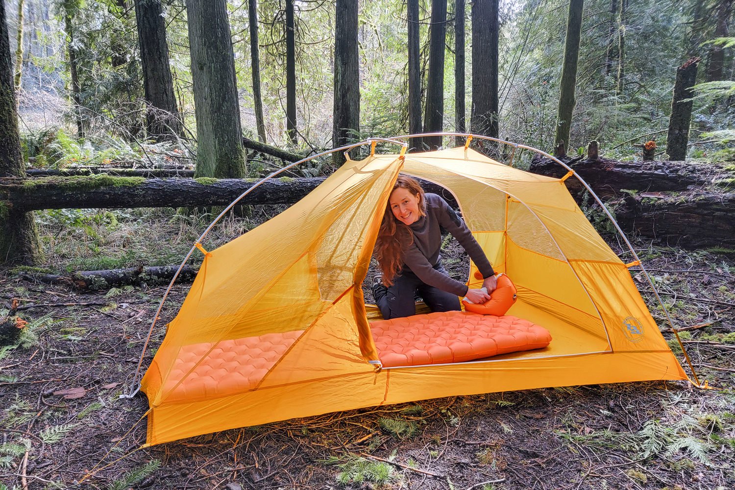 A hiker inside a tent smiling as she blows up the Big Agnes Zoom UL with a pump sack