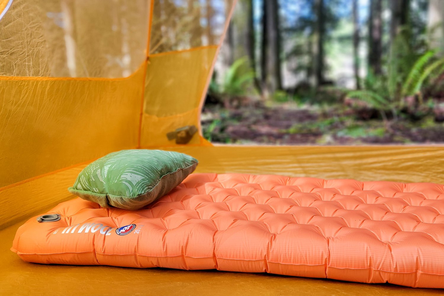 The Big Agnes Zoom UL sleeping pad in a tent with a pillow on top - the tent door is open and theres a forest in the background