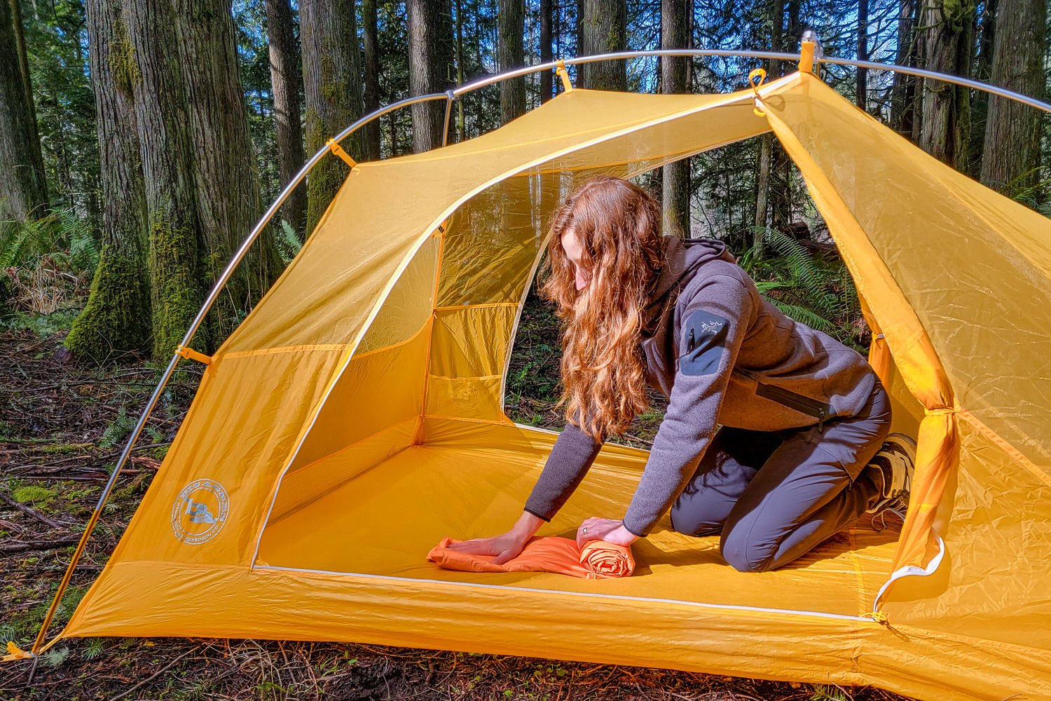 A hiker kneeling in a tent rolling up the Big Agnes Zoom UL