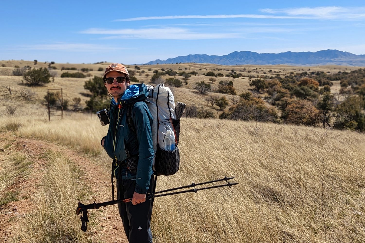 A side view of a hiker wearing the Hyperlite Mountain Gear Unbound 40 on a desert trail with distant mountains in the background