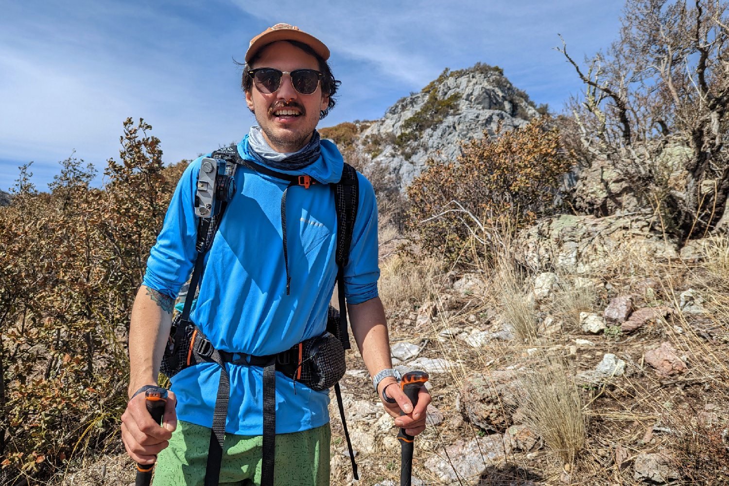 A front view of a smiling hiker wearing the Hyperlite Mountain Gear Unbound 40 with a mountain behind him