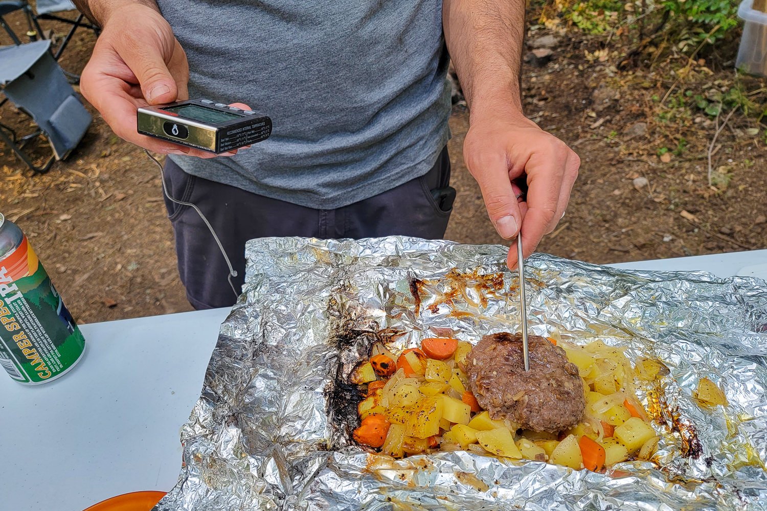 Using a meat thermometer to check a foil packet meal for doneness