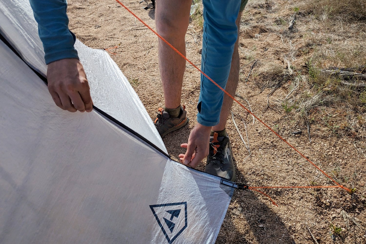 A top down view of a hikers hands zipping the vestibule of the Hyperlite Unbound 2P tent