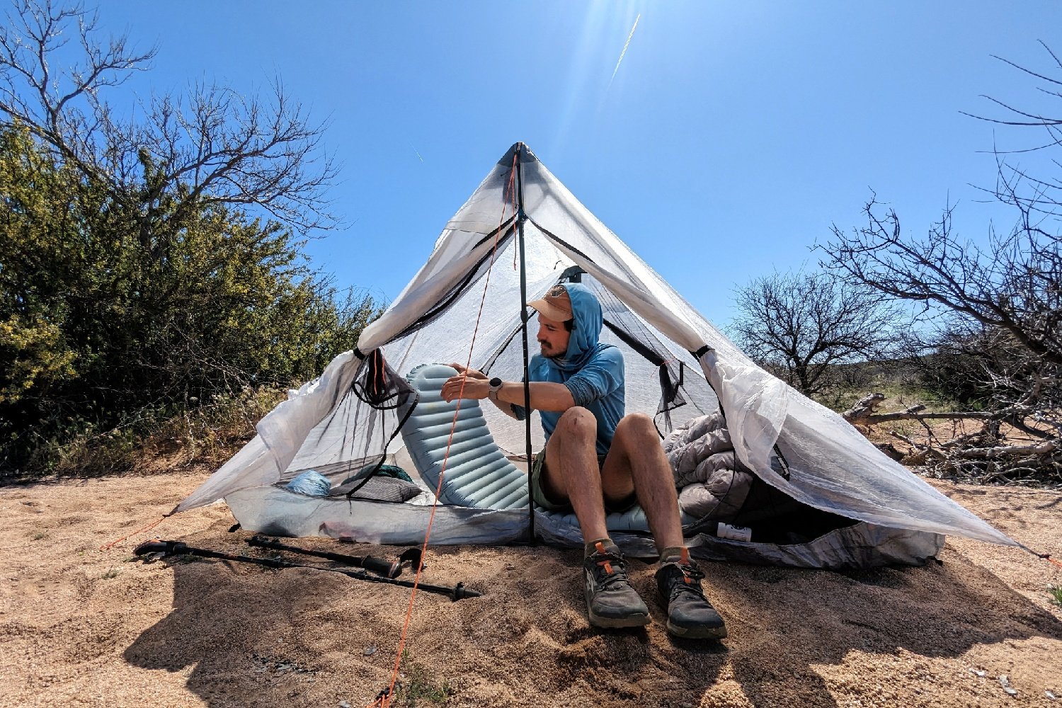 A hiker sitting inside the HMG Unbound 2 holding a sleeping pad with his legs sticking out of the front