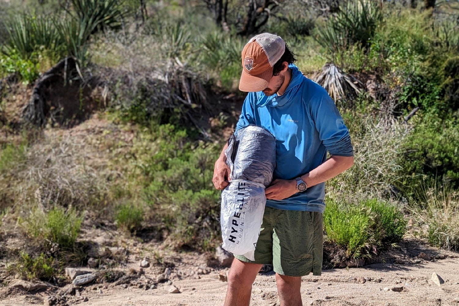 A hiker putting the rolled up Hyperlite Unbound 2 tent into a stuff sack