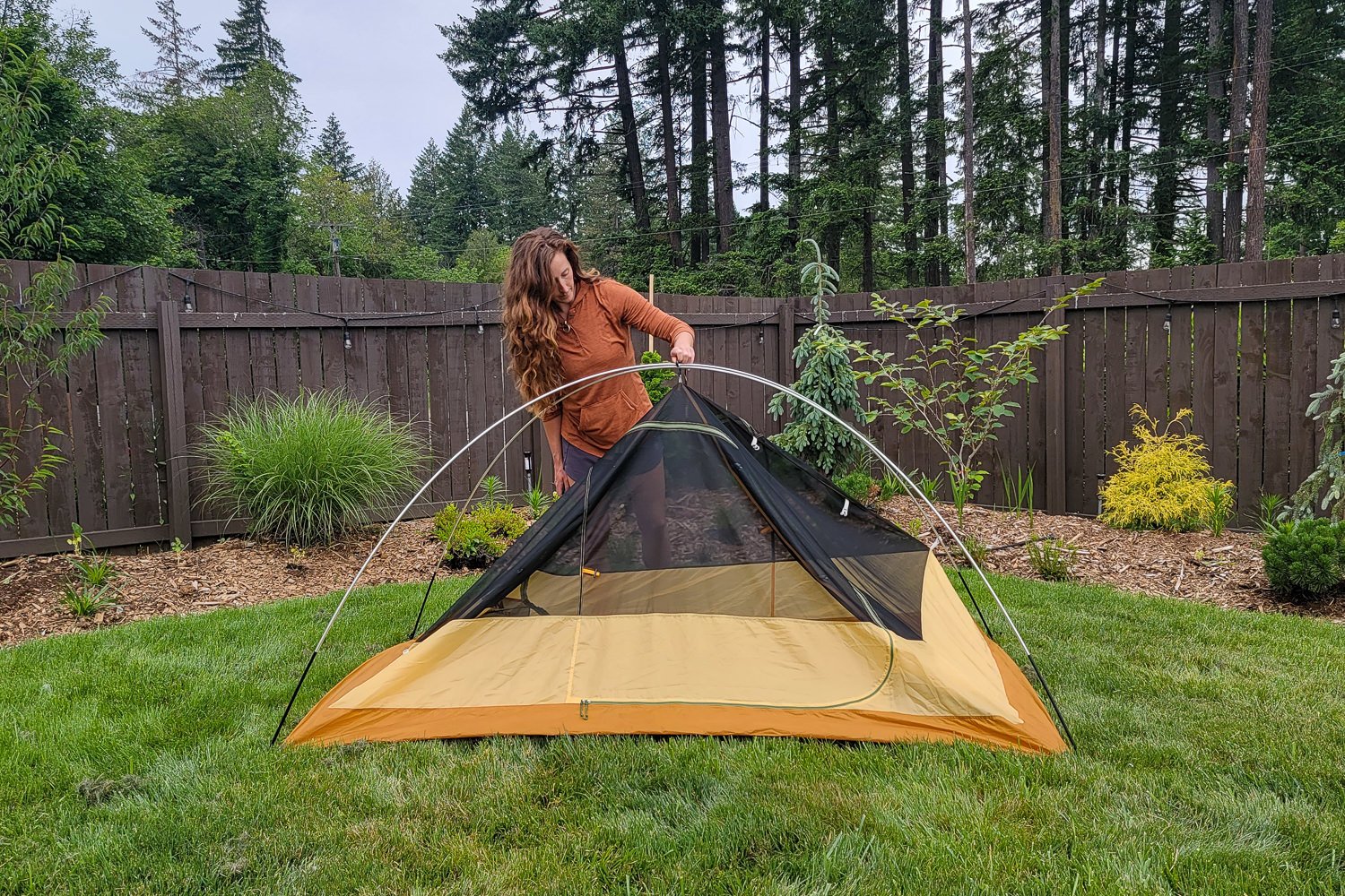 A woman setting up the REI Trailmade 2 in a backyard