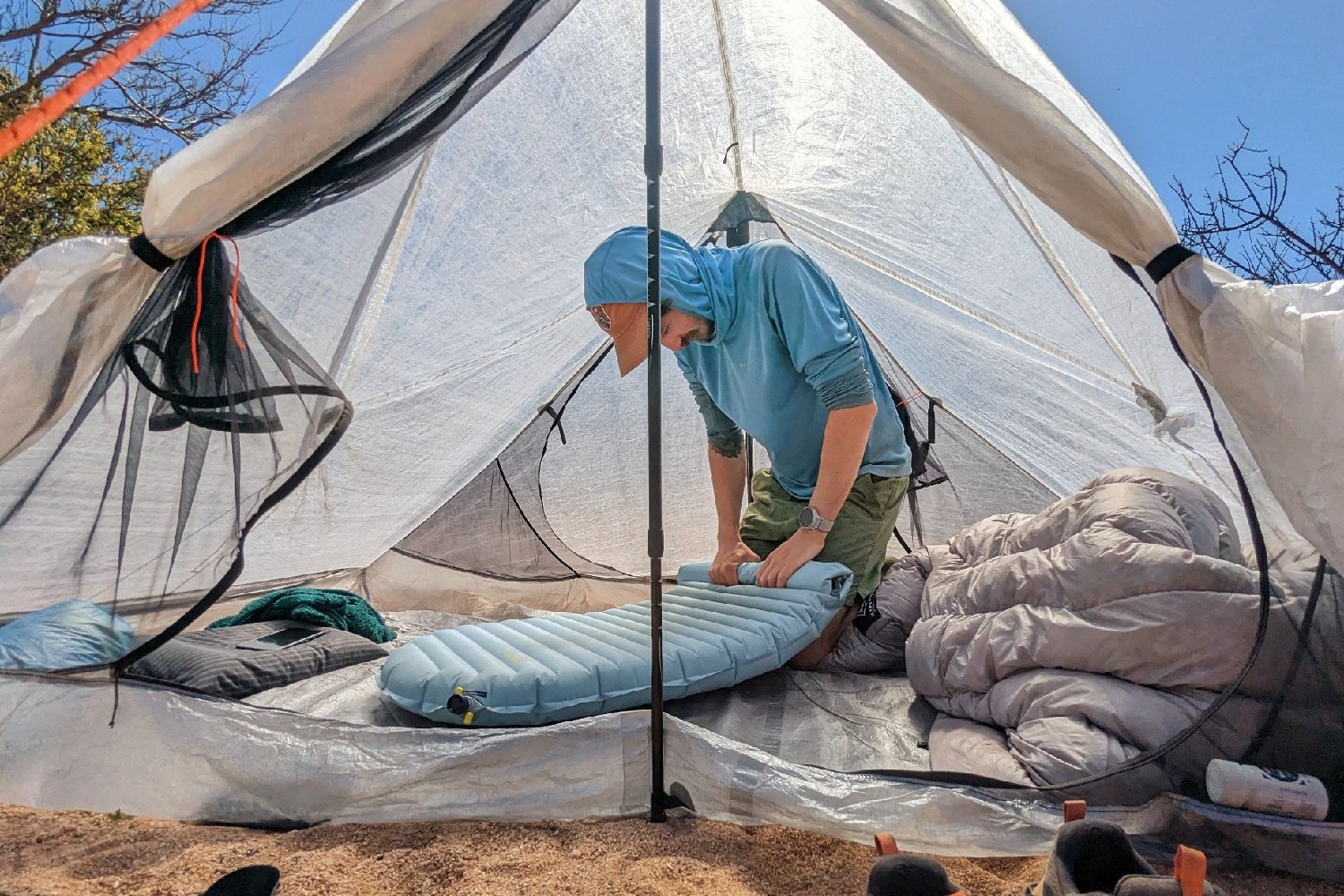 A hiker in a tent rolling air out of the Therm-a-Rest NeoAir Xtherm NXT sleeping pad