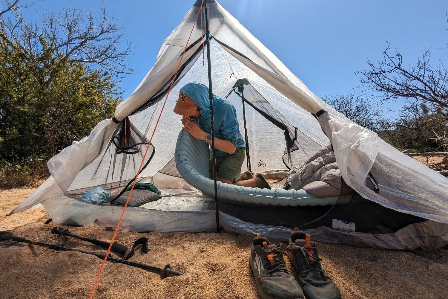 A hiker in a tent in a desert campsite blowing up the Therm-a-Rest NeoAir Xtherm NXT by mouth