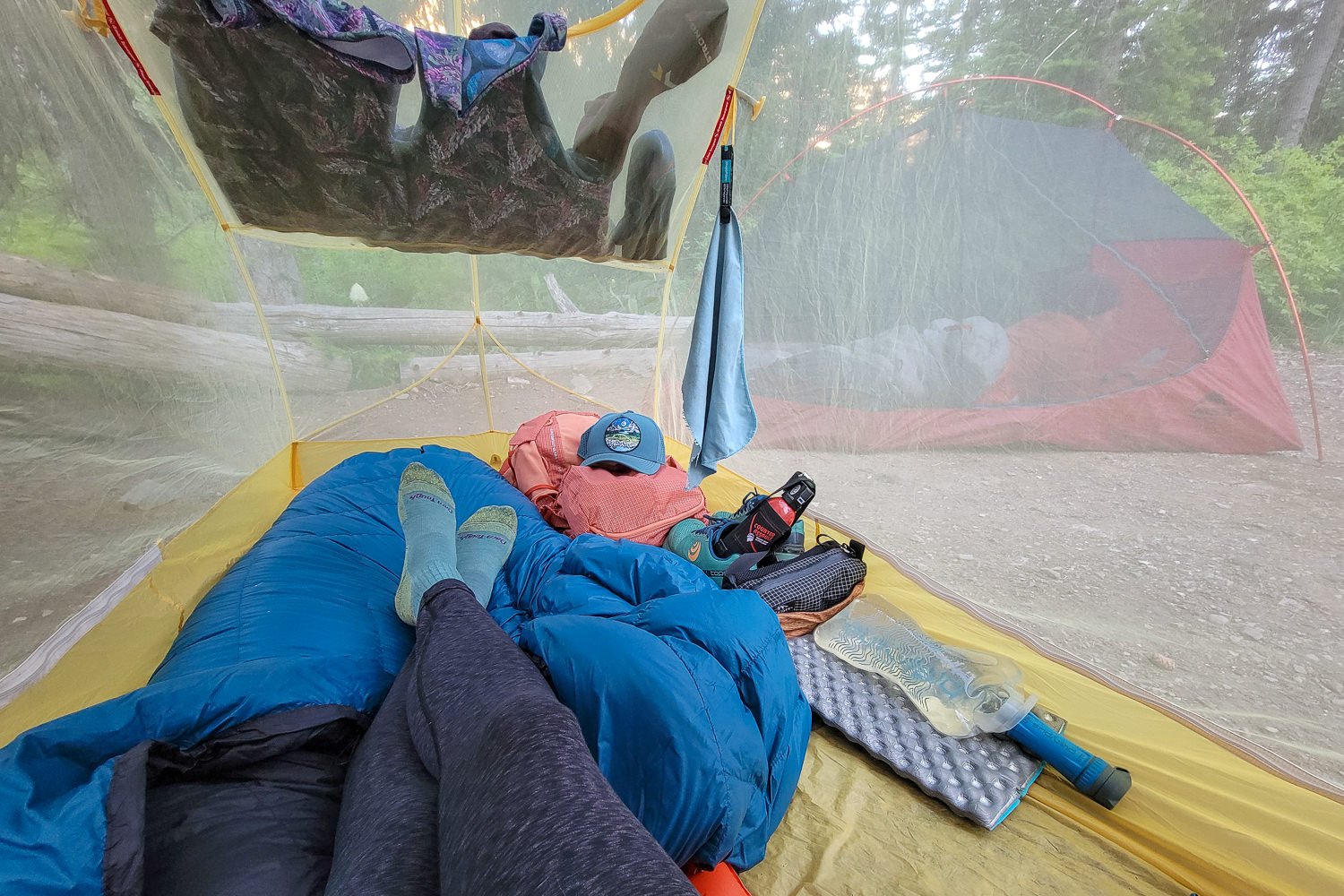 A hiker resting in a backpacking tent with the Platypus QuickDraw at her side