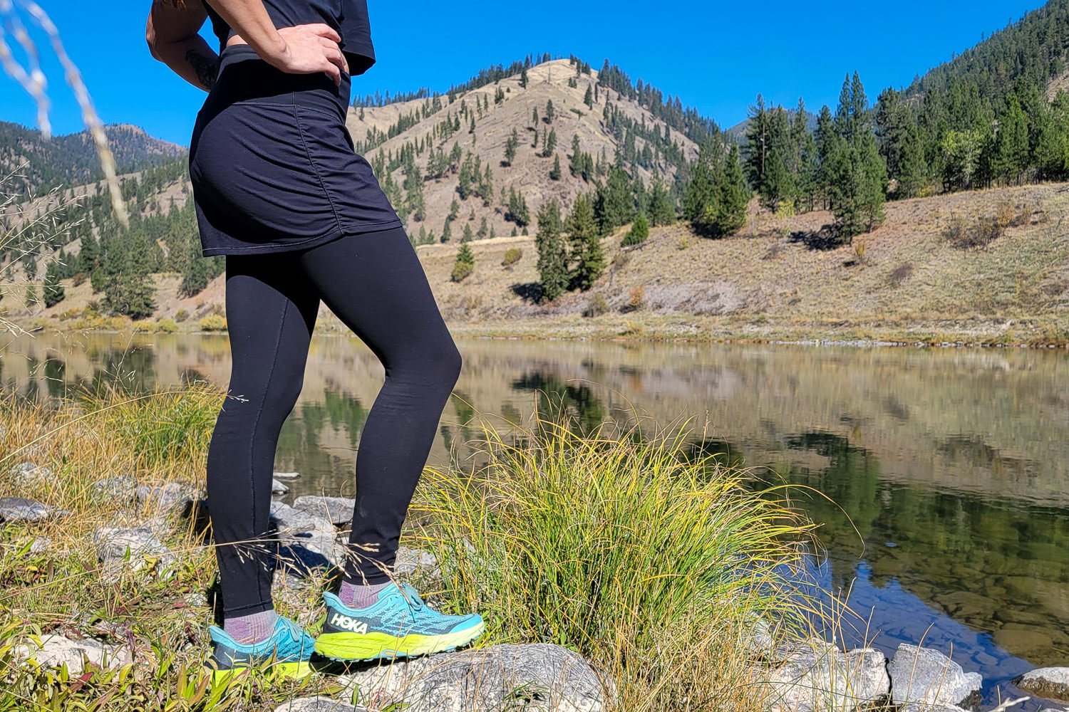 A hiker wearing the Athleta Elation 2 in 1 Leggings by a river