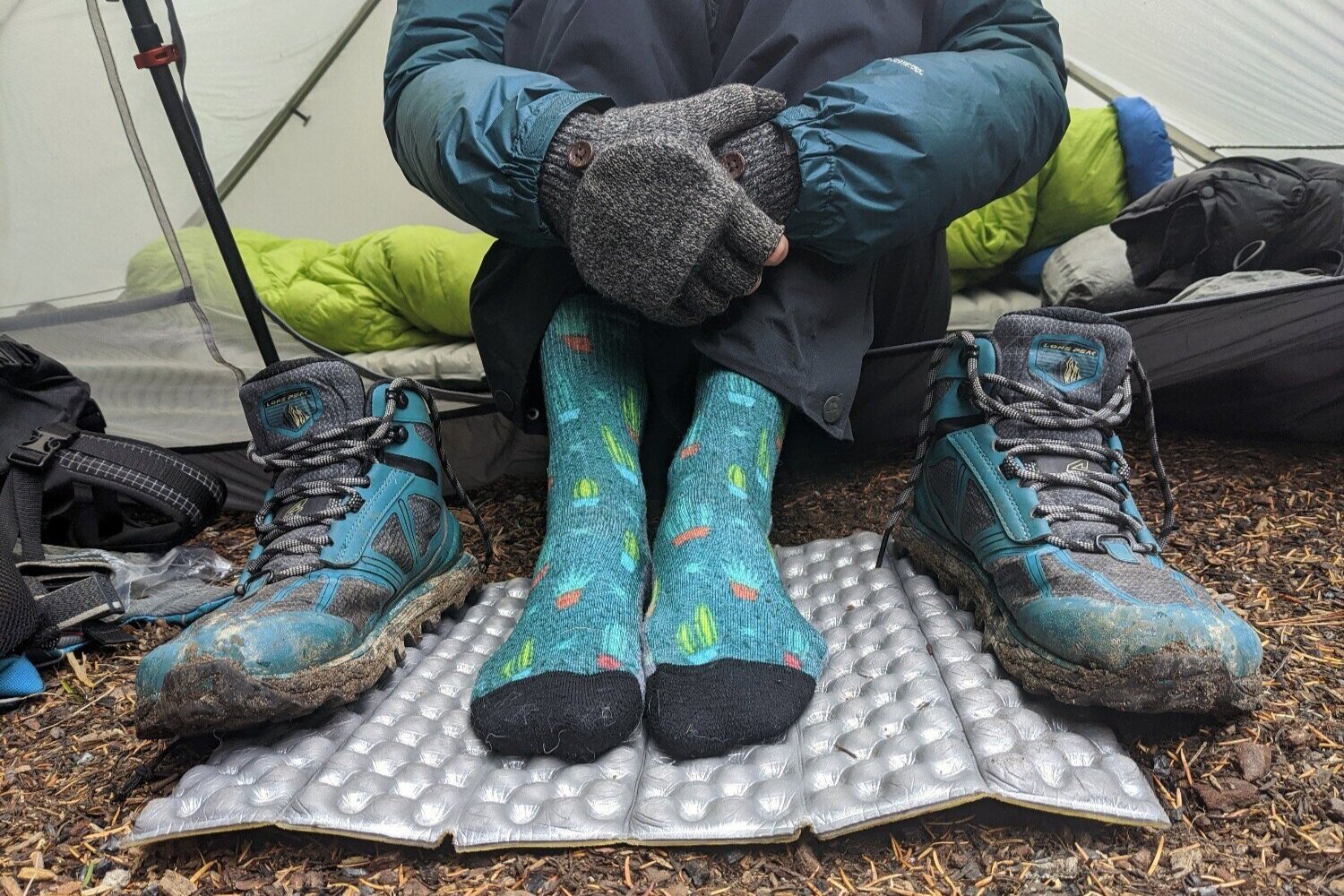 A backpacker sitting in a tent wearing Smartwool PhD Outdoor Light Crew Socks, the socks are patterned and blue
