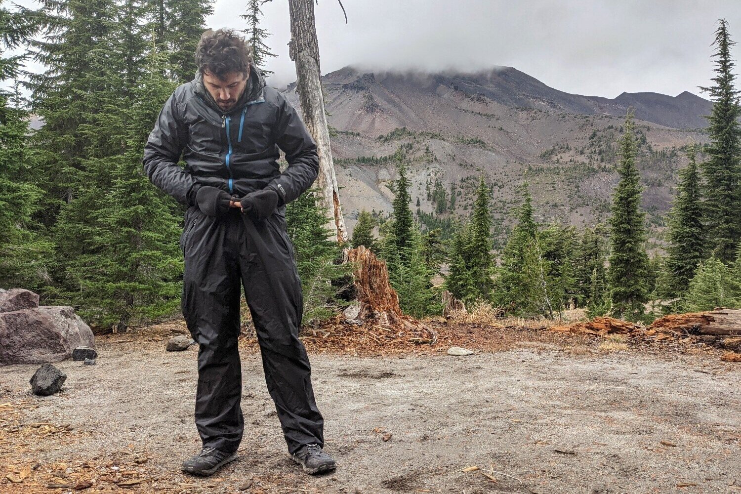 https://www.cleverhiker.com/wp-content/uploads/2023/08/A-hiker-adjusting-the-drawstring-on-the-REI-Rainier-Full-Zip-Rain-Pants.jpeg