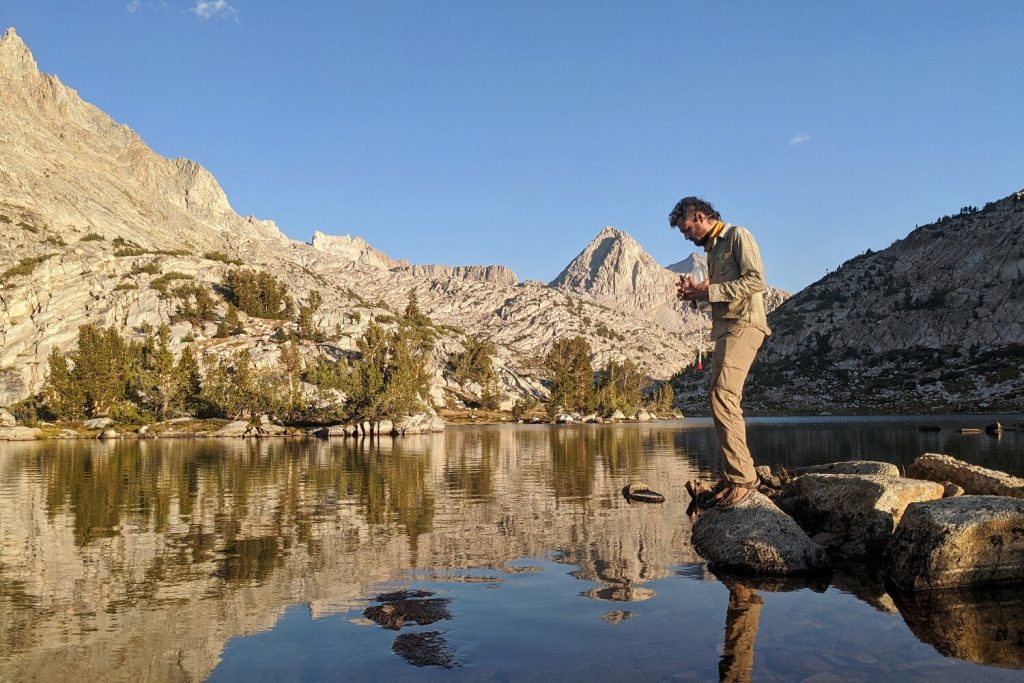 A hiker standing next to a lake with a mountain view