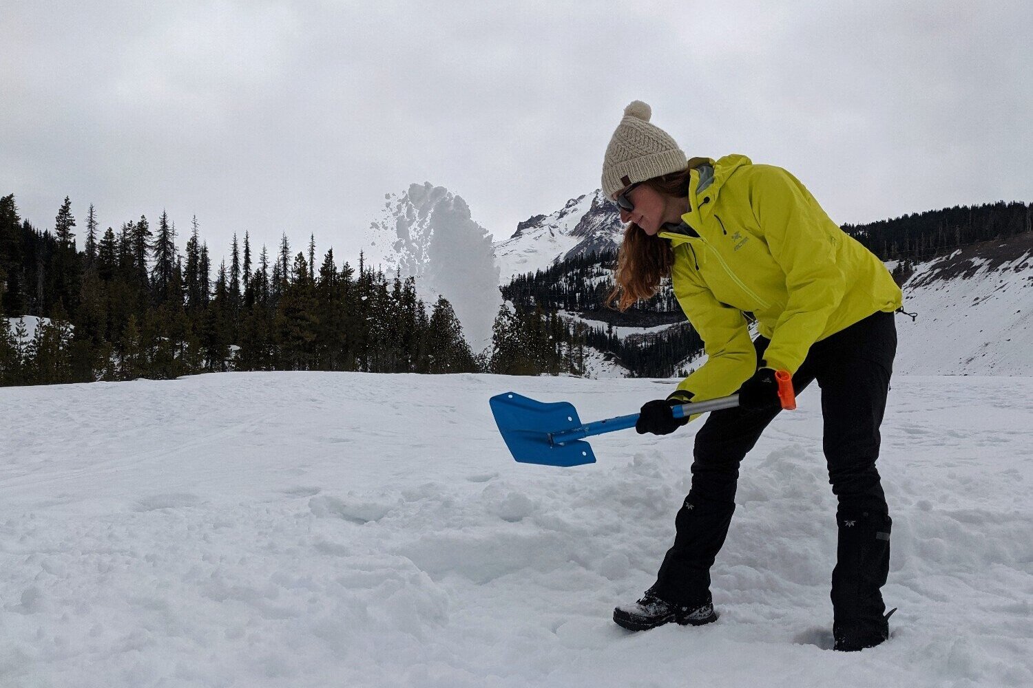 A+hiker+using+a+snow+shovel+to+dig+out+a+campsite