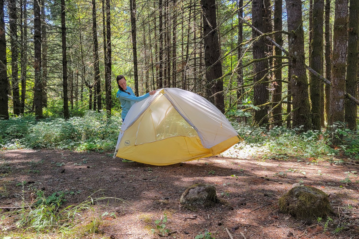 A hiker picking up the Big Agnes Tiger Wall UL2 tent and repositioning it in a campsite