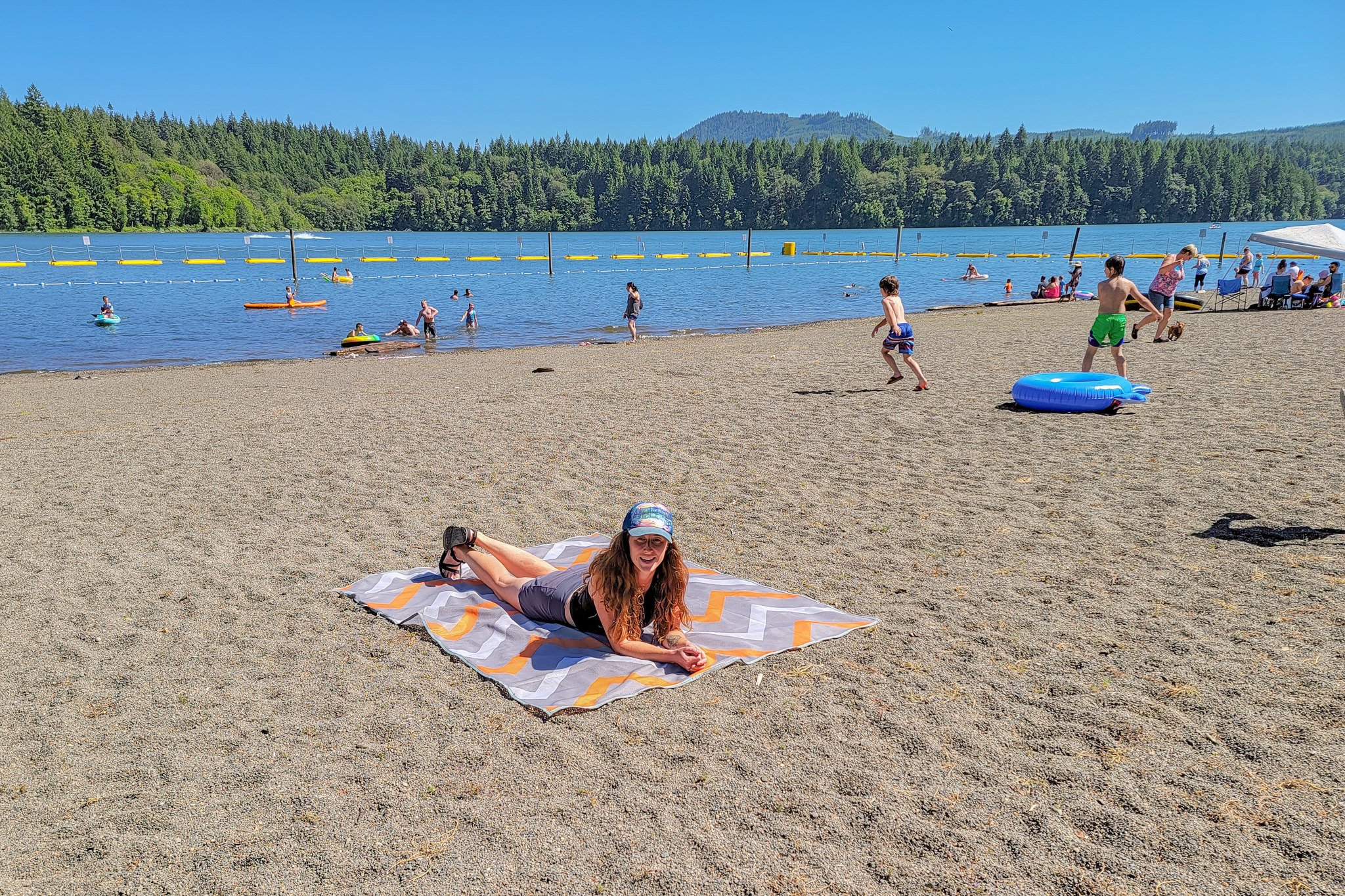 A woman using the CGear Sandlite Mat at a swimming area on the river