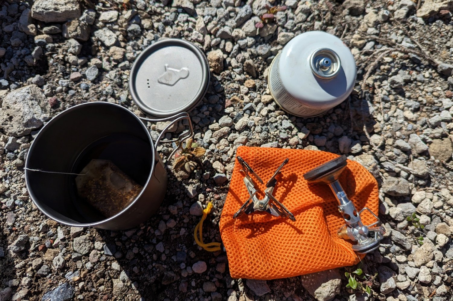 The SOTO Windmaster stove laid out next to a cookpot and fuel canister with the removable 4Flex pot support next to it