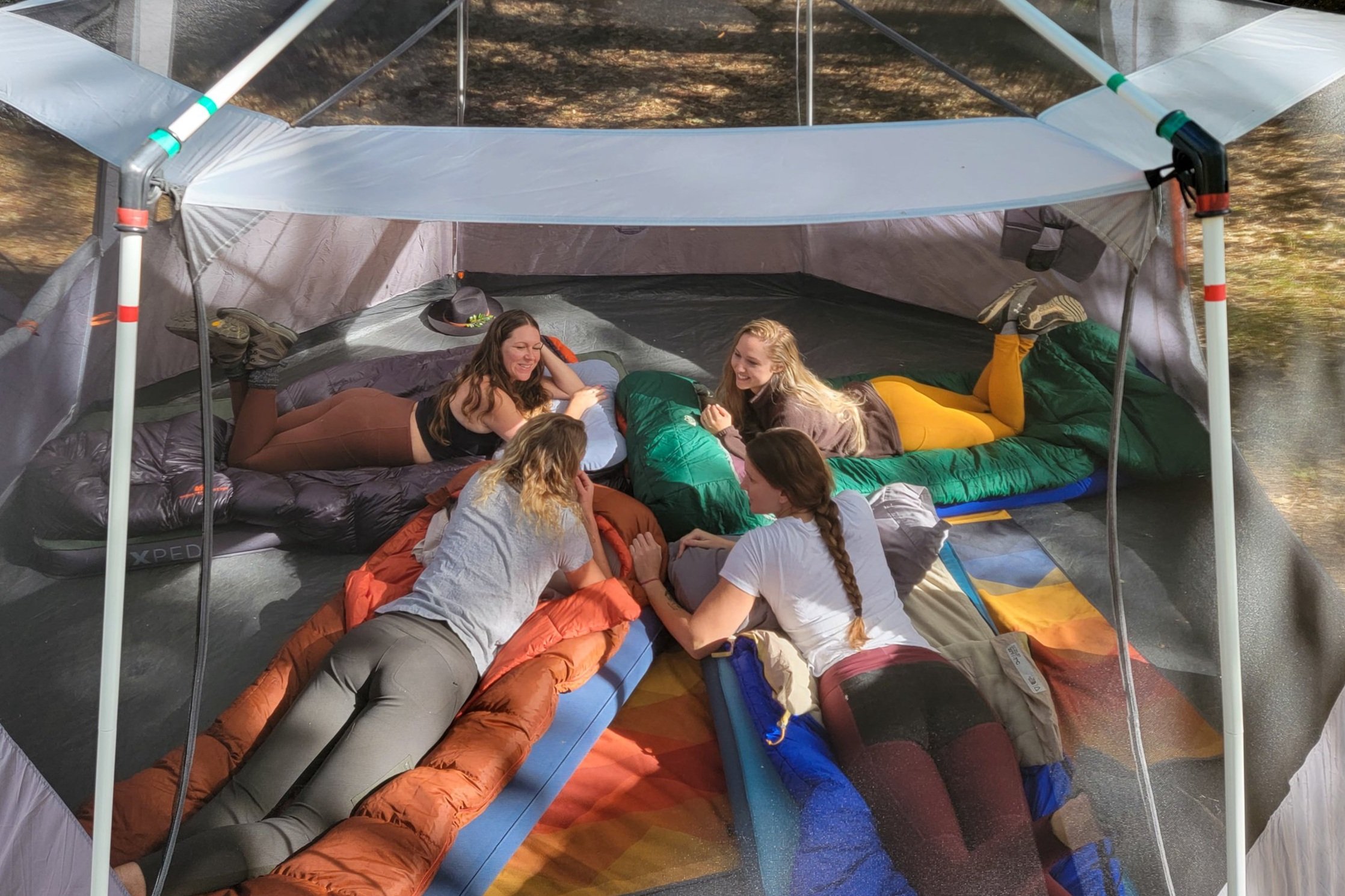 A group of women laying on sleeping bags in a large camping tent
