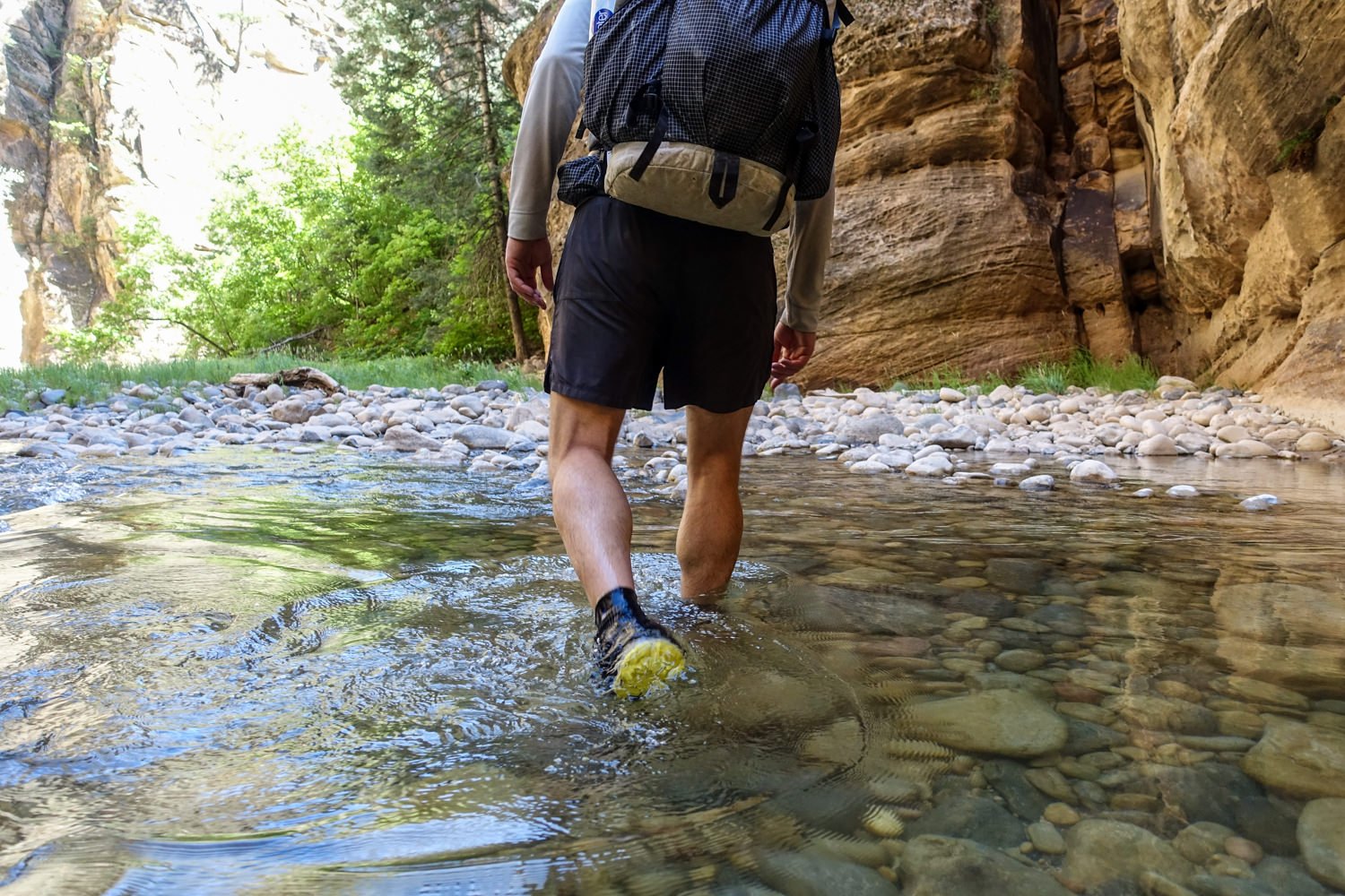 A hiker walking through a river in Nike DRI Fit Challenger Shorts