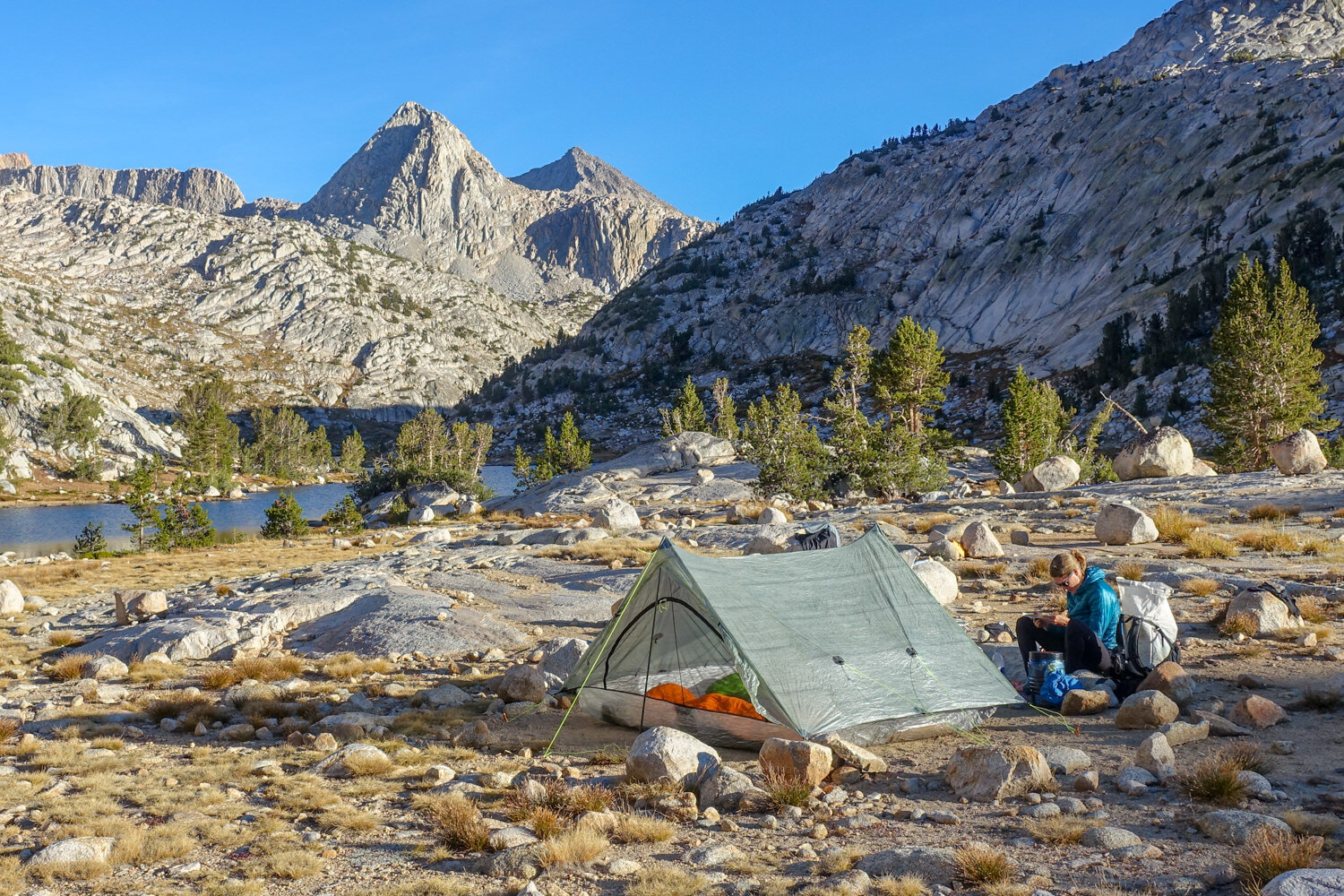 The Zpacks Triplex and a backpacker in a campsite surrounded by granite peaks along the John Muir Trail