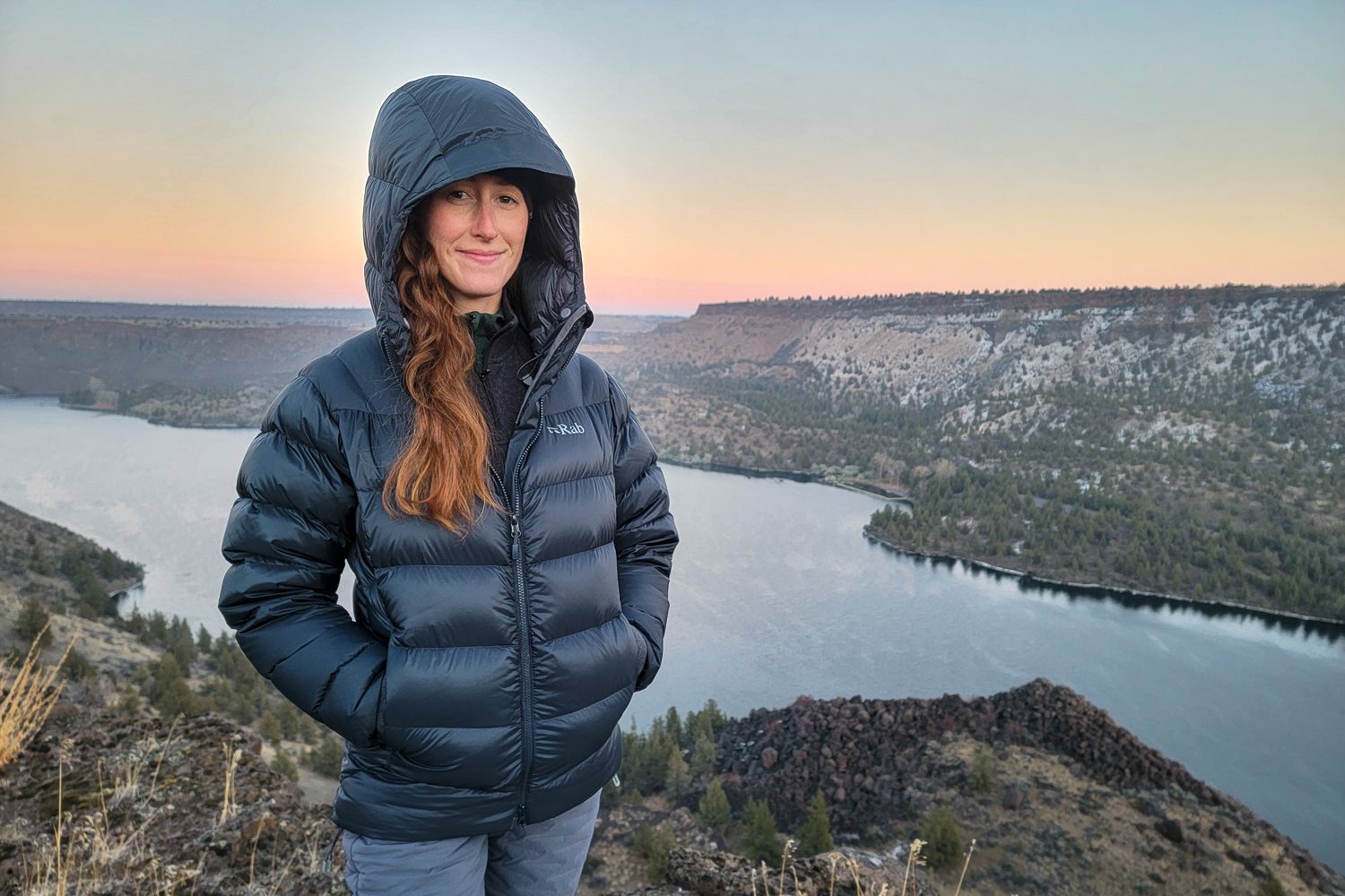 A woman wearing the Rab Neutrino Pro on a winter camping trip in the high desert