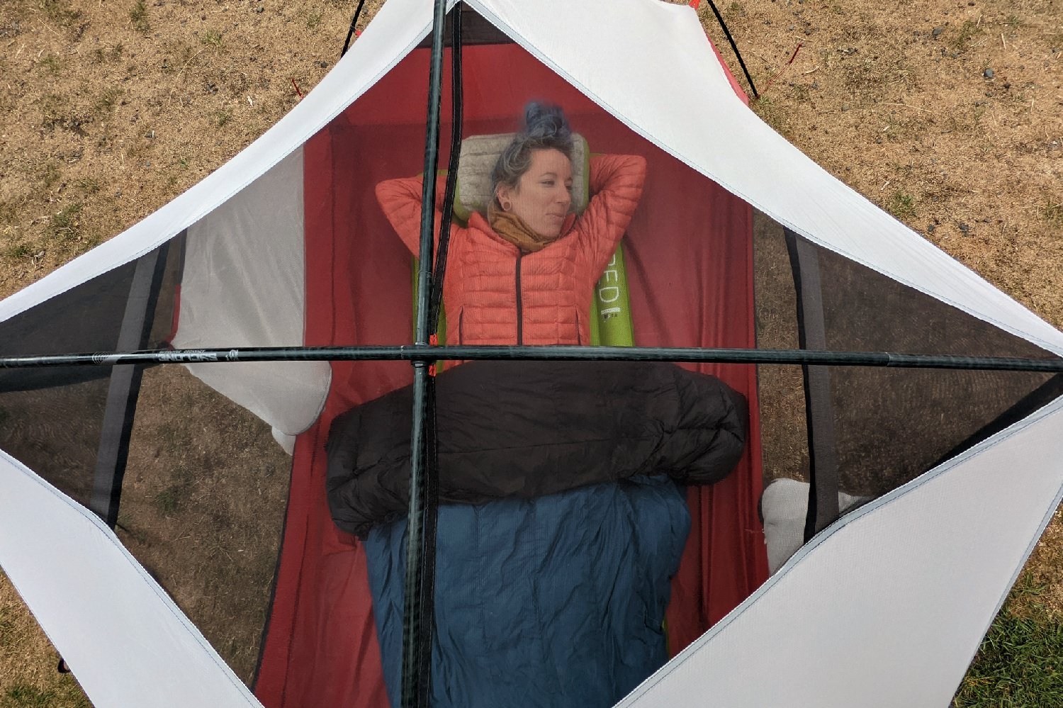 A hiker in a tent pictured from above relaxing in a tent with a Hammock Gear Econ Burrow Quilt